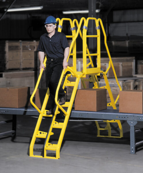 a man descends yellow Lapeyre crossover alternating tread stairs over a conveyor belt