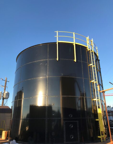 a black epoxy-coated bolted Tarsco tank with yellow ladder and rails
